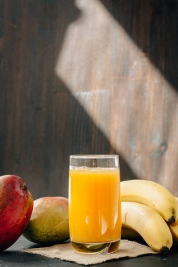 Cam siyah yüzey üzerinde muz ve mango suyu ile dolu