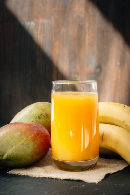 Cam siyah yüzey üzerinde muz ve mango suyu ile dolu