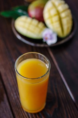 Arka planda mango meyveleri olan taze tropikal mango suyu.