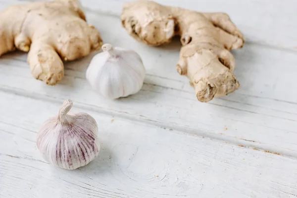 Garlic and ginger on white wooden surface