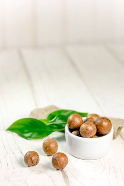 Macadamia fındık ahşap masa üzerinde beyaz seramik kase