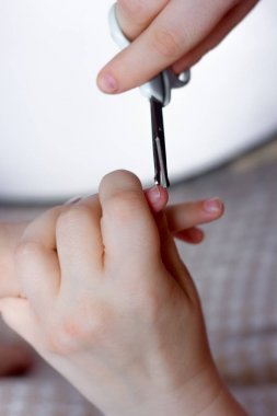 Anne küçük kızın parmağında tırnak kesti.