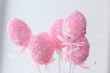 Beyaz arka plandaki çubuklarda pembe paskalya yumurtaları.