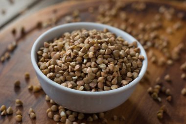 Tahta masanın üzerinde seramik kasede karabuğday taneleri