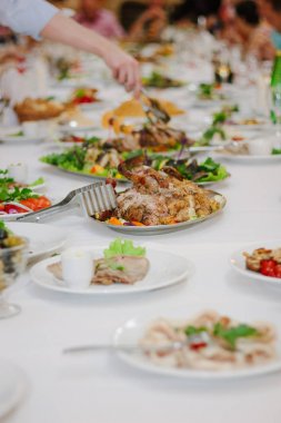 Yemek masası. Elinde maşayla yemek yiyor.