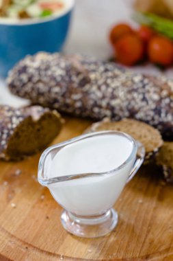 Tahtadaki şeffaf cam kasede krema sosu..