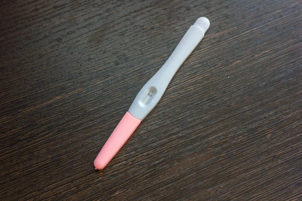 Negative pregnancy test over the brown wooden surface. — Stock Photo, Image