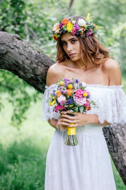 Çiçek buketi ve çiçekli gelinlik içindeki güzel gelin..