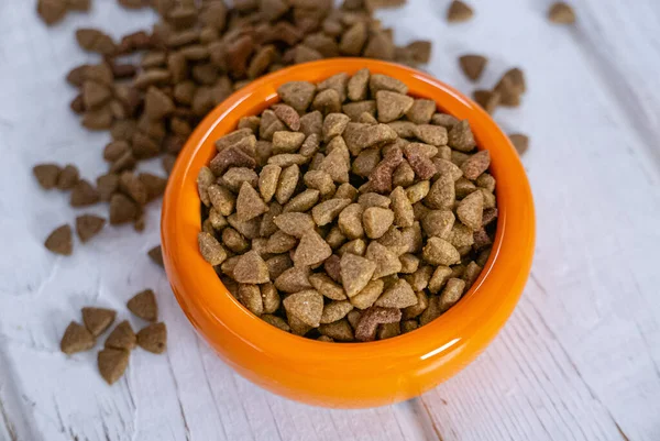 Dry pet food in a orange bowl.