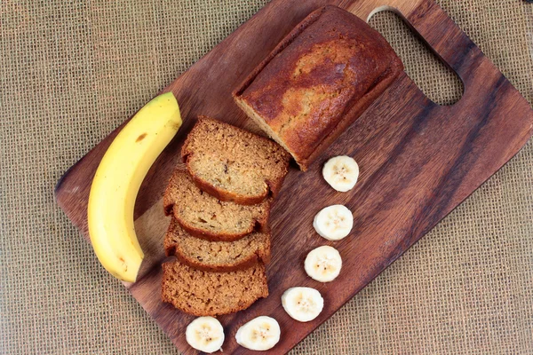 Homemade banana cake with sliced banana and whole banana on butcher served.