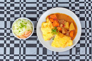 Omlet pirinç Japon sarı köri dilimlenmiş lahana ve turşu zencefil ile tepesinde.