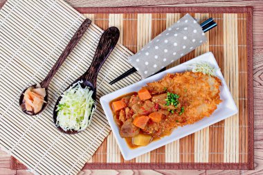 Japon tarzı derin kızarmış dolly balık dilimlenmiş lahana ve turşu zencefil ile sarı köri tepesinde.