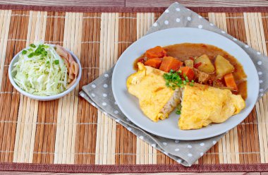 Omlet pirinç Japon sarı köri dilimlenmiş lahana ve turşu zencefil ile tepesinde.