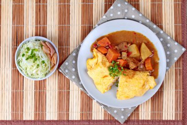 Omlet pirinç Japon sarı köri dilimlenmiş lahana ve turşu zencefil ile tepesinde.