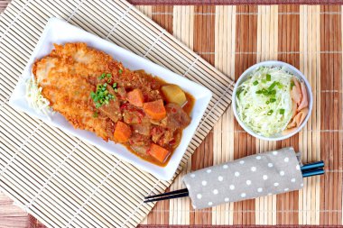 Japon tarzı derin kızarmış dolly balık dilimlenmiş lahana ve turşu zencefil ile sarı köri tepesinde.