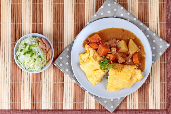 Omlet pirinç Japon sarı köri dilimlenmiş lahana ve turşu zencefil ile tepesinde.