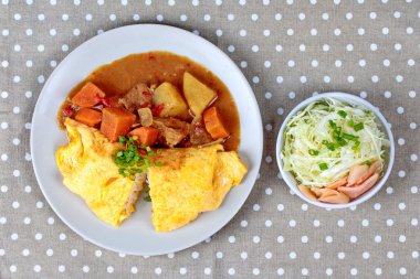 Omlet pirinç Japon sarı köri dilimlenmiş lahana ve turşu zencefil ile tepesinde.