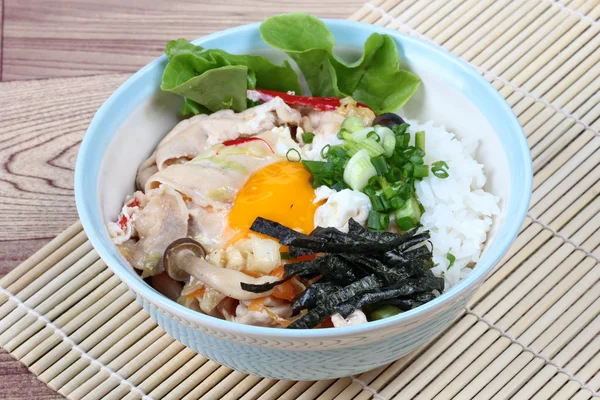 Gros plan de riz au jasmin est surmonté d'œufs à ébullition molles et de porc frit dans le style japonais comme "Oyakodon" avec un plat d'accompagnement comme feuille d'algue séchée tranchée et gingembre mariné. Concentration sélective . — Photo