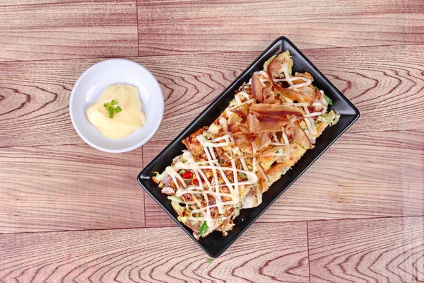 Pizza de Japón como "Okonomiyaki" se fríe harina vegetal mixta con salsa dulce cubierta de carne, mayonesa o crema de ensalada y atún amarillo seco en rodajas servido con guarnición . — Foto de Stock