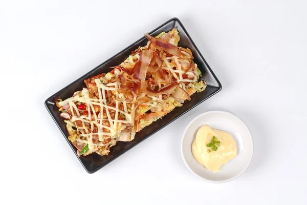 Pizza de Japón como "Okonomiyaki" se fríe harina vegetal mixta con salsa dulce cubierta de carne, mayonesa o crema de ensalada y atún amarillo seco en rodajas servido con guarnición . — Foto de Stock