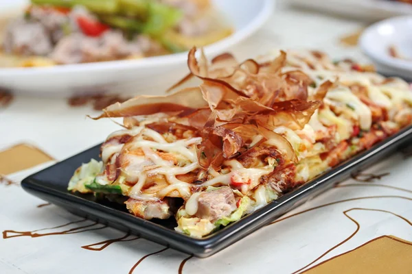 Close up Japan pizza as "Okonomiyaki" is fried mixed vegetable flour with meat topped sweet sauce, mayonnaise or salad cream and sliced dry yellowfin tuna served with side dish. Enfoque selectivo . — Foto de Stock