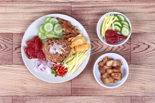 Gebratener Jasminreis mit Garnelenpaste nennen "kao kook kapi" in Thailand serviert mit grünem Sauermangobrötchen, chinesischer Wurst, knusprigem Trockenfisch, Garnelen, gehacktem Chili, Schalotten, süßem Schweinefleisch, geschnittenen Gurken und Rührei . — Stockfoto