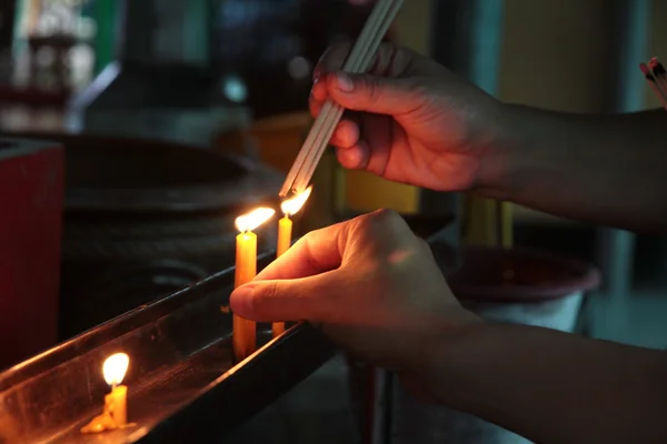 Buddhisten verdienen, indem sie eine brennende Kerze und entzündeten Weihrauch mit Kerzen Rahmen auf dem Altar des Buddha im Tempel platzieren. Selektiver Fokus — Stockfoto