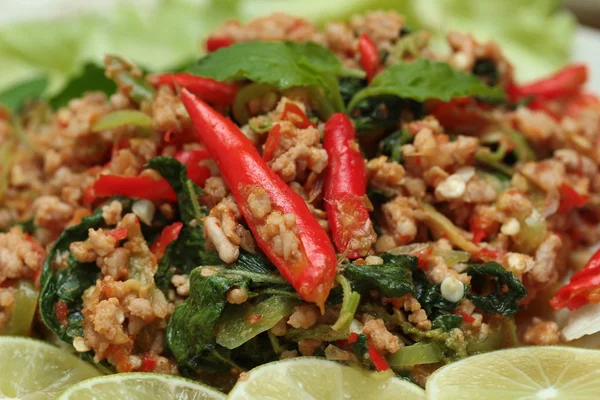 Close up of fried spicy basil with minced pork topped sliced green lemon and and lettuce is top ten of popular Thai food. Selective focus. — Stock Photo, Image