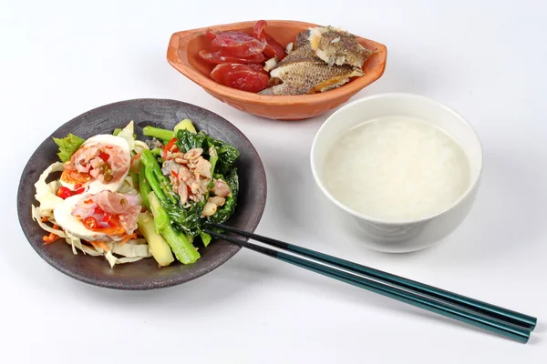 Gruau de riz et accompagnement comme râpé de poisson frit séché au soleil, saucisse chinoise, salade d'œufs salés épicés et chou frite au poisson salé . — Photo
