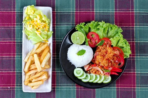 Hausgemachter Jasminreis mit würzigem gebratenem Hühnchensalat (khao yum kai zap in thai) garniert mit Gurkenscheiben, Tomaten, halbierter Zitrone und Salat, serviert mit gemischtem Gemüsesalat und französischem Feuer. — Stockfoto