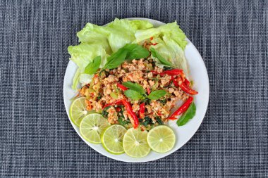 Kızarmış baharatlı fesleğen kıyılmış domuz tepesinde ile dilimlenmiş yeşil limon ve ve marul