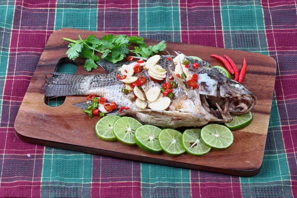 Tilapia fish streamed with lemon topped spicy sour ginger and chili on butcher served. (Call Pla Nil Nuang Manoaw in Thai) isolated white background.