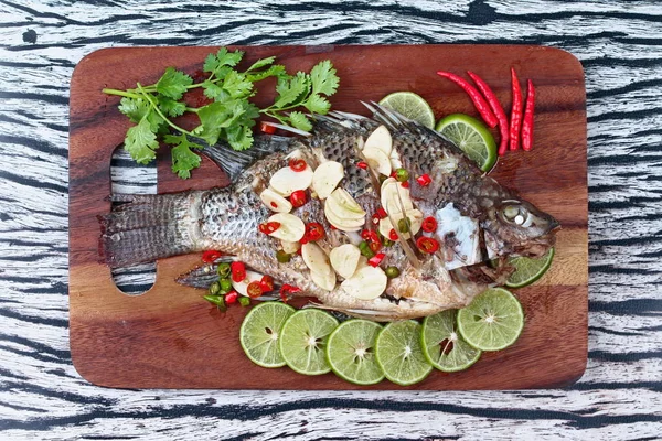 Tilapia fish streamed with lemon topped spicy sour ginger and chili on butcher served. (Call Pla Nil Nuang Manoaw in Thai)