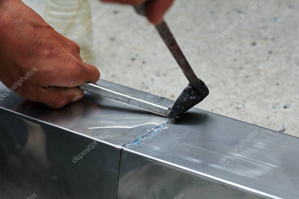 Aluminium gutter welding by using soldering copper with picnic gasTechnician is welding