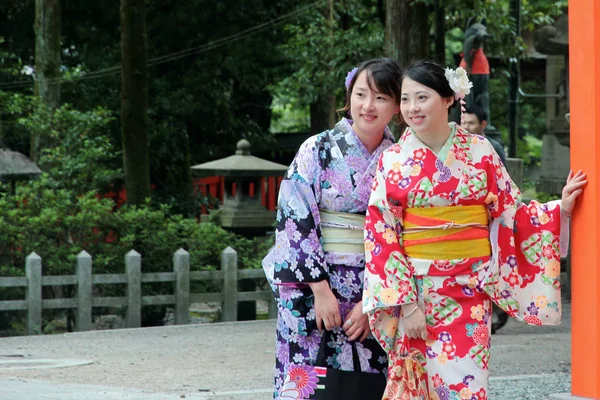 Quimonos de duas mulheres postam e sorriem para foto dentro do santuário . — Fotografia de Stock