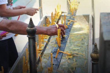 Buda'nın sunağına bir mum yerleştirerek.