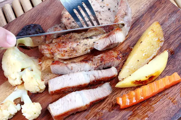 Utilice cuchillo y tenedor para cortar carne de cerdo en rodajas  . — Foto de Stock