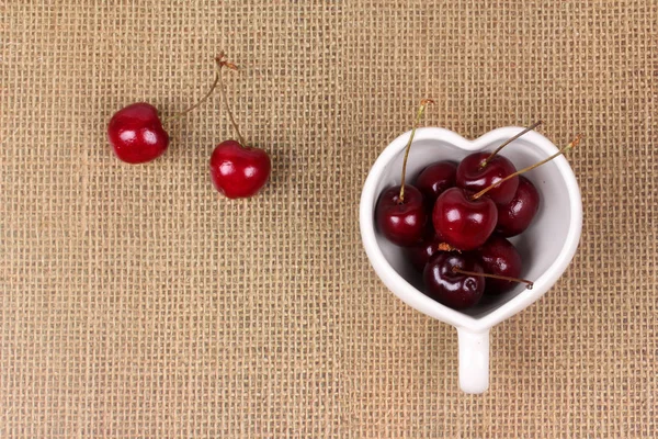 Cerejas Chile e caneca em forma de coração em pano de saco . — Fotografia de Stock