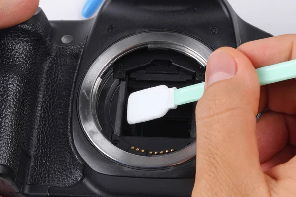 Photographer hand cleaning sensor of camera by using sensor swab