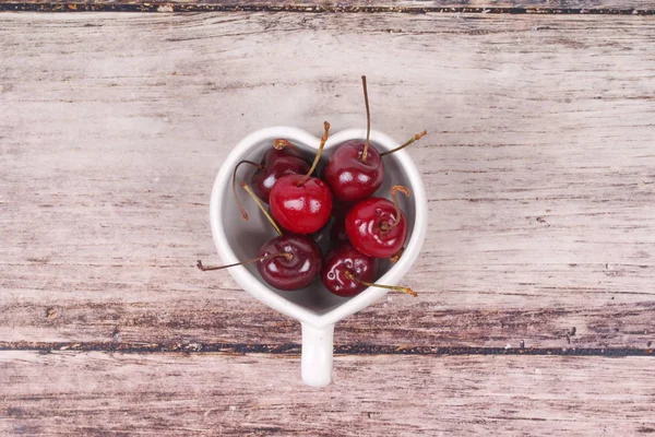 Kiraz Şili ve kalp şeklinde kupa üzerinde ahşap.