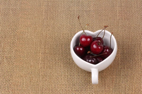 Cerises Chili et tasse en forme de coeur sur sac . — Photo