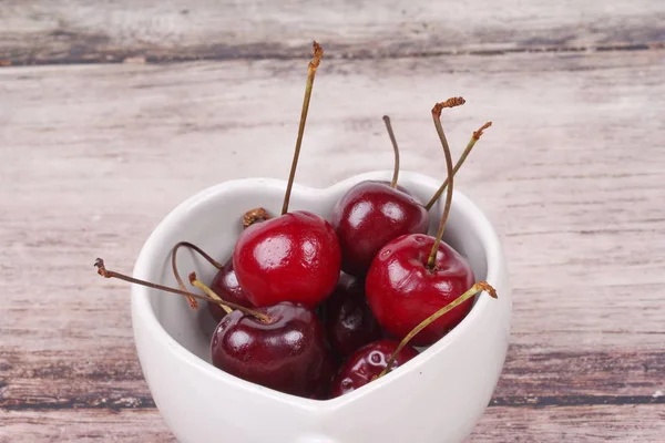 Cerises Chili et tasse en forme de coeur sur bois . — Photo