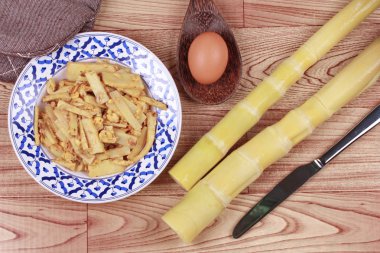Fried yumuşak bambu kutup sürgünleri ile yumurta ve mutfak ekipmanları coo