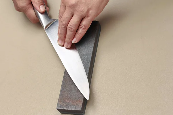 Maneja el cuchillo para hacer un cuchillo afilado con una piedra de afilar . —  Fotos de Stock