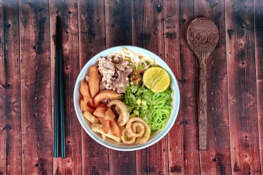 Yeşil noodle ile tepesinde tom yam kıyılmış domuz, tavuk karaciğer ve v