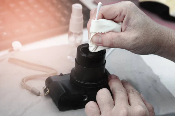 Photographer hand cleaning sensor of camera by using sensor swab