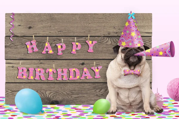 pug puppy dog with pink party hat and horn and wooden sign with text happy birthday, on light pink background