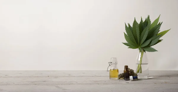 Pankartta cam şişede Cbd yağı, kenevir sativa marihuana ot yaprakları ve damlalık şişesi, endüstriyel ahşap zemin katta