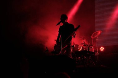 Karanlık bir arka planda bir gitaristin silueti. Şarkı söyler ve gitar çalar.