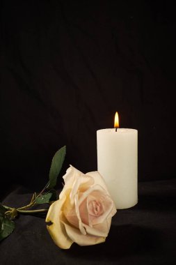 Yanan mum ve siyah arka planda güzel bir gül.